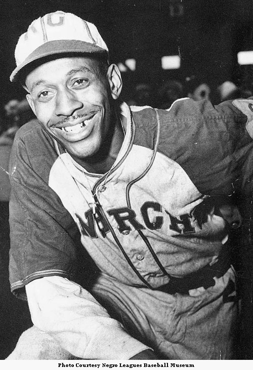 Untitled photo shows: Satchel Paige, in the Kansas City Monarchs uniform at  a baseball game]