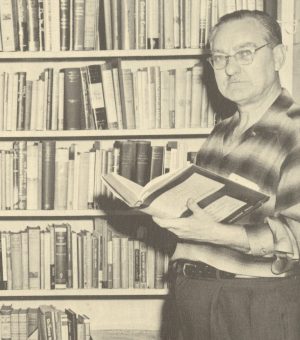 Vincent Bucher standing beside his father's collection of books, date unknown. [Ozark Stories of the Upper Current River, p. 64. SHS REF F586 V663]